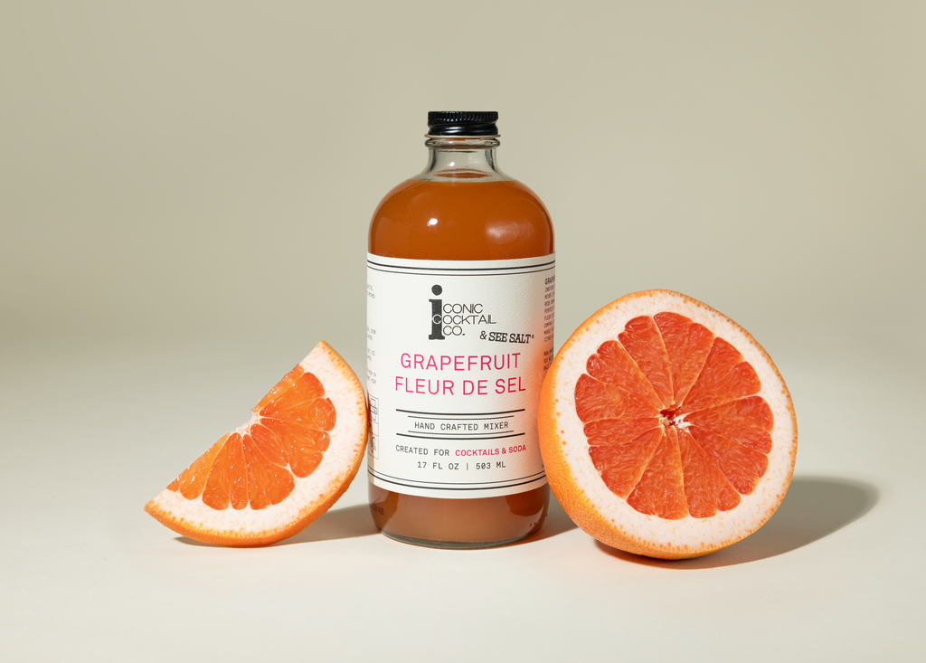 Bottle of grapefruit syrup with a halved grapefruit on a beige background
