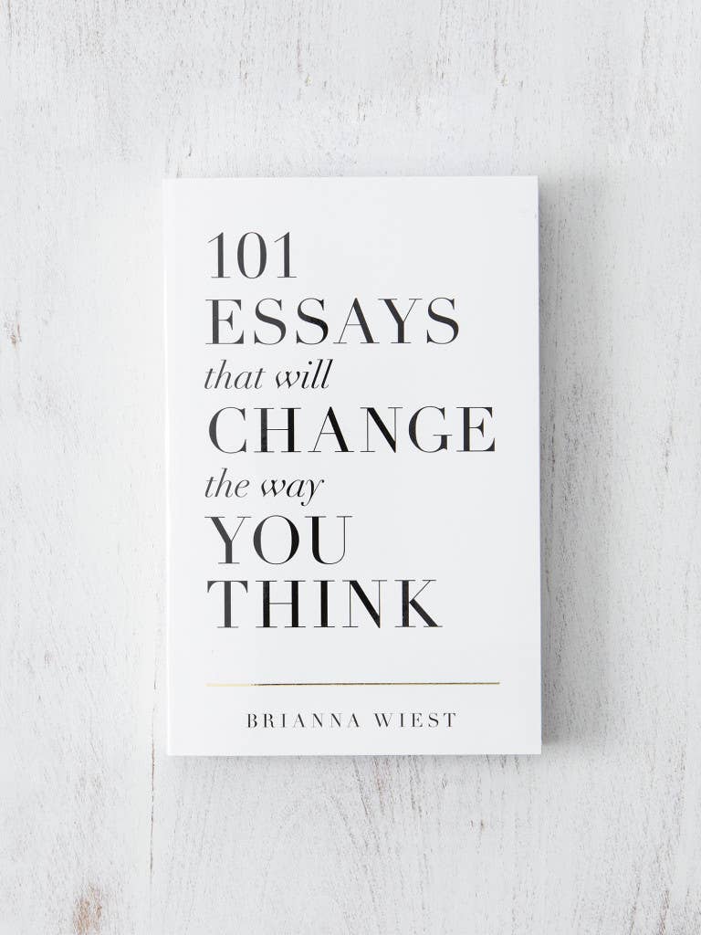 A white paperback book titled '101 Essays That Will Change The Way You Think' by Brianna Wiest, laid on a white wooden surface.