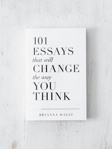 A white paperback book titled '101 Essays That Will Change The Way You Think' by Brianna Wiest, laid on a white wooden surface.