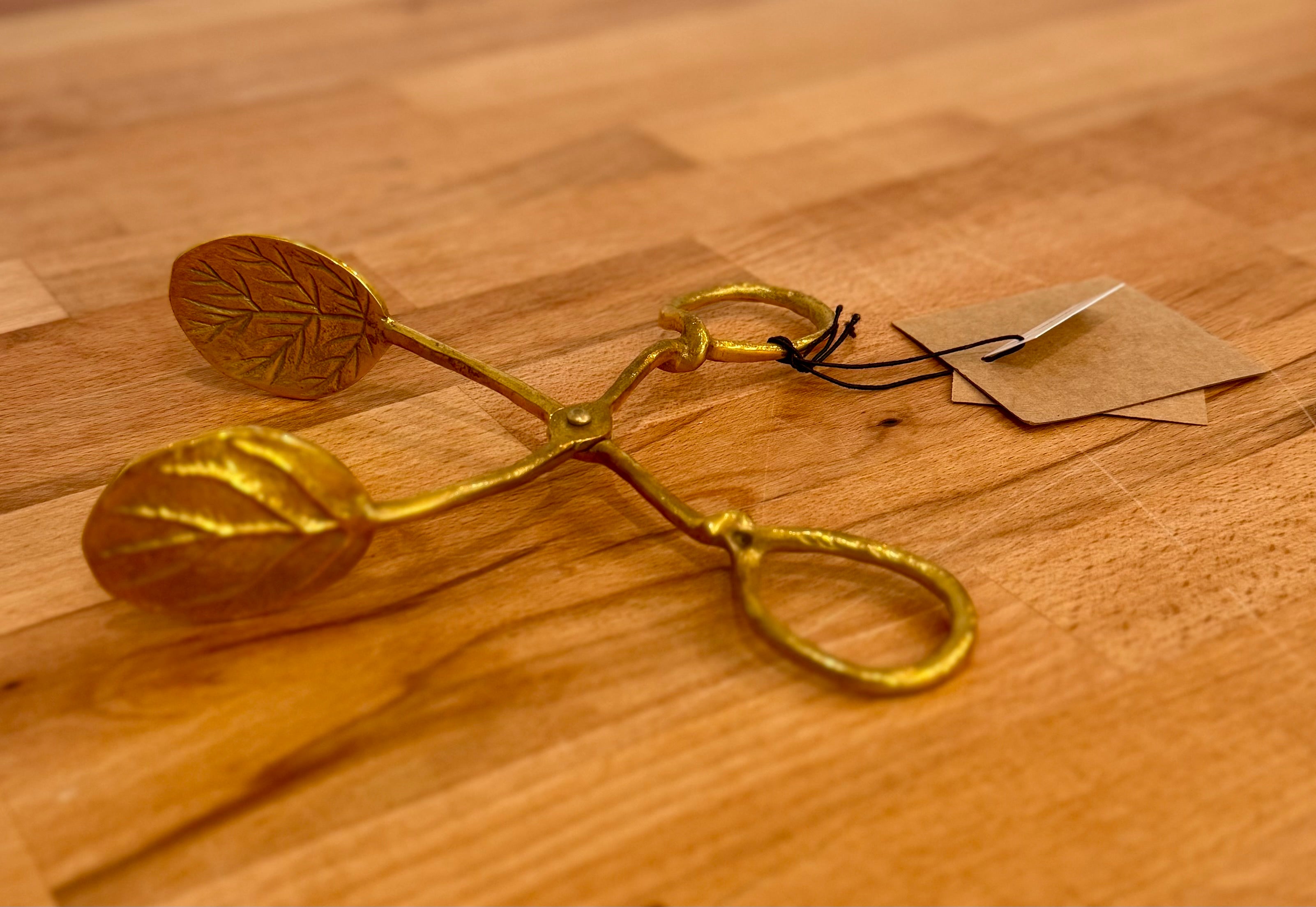 Gold-colored kitchen tool on a wooden surface with a tag.