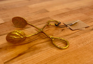 Gold-colored kitchen tool on a wooden surface with a tag.