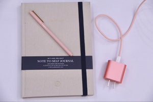 cream lined notepad with rose pen on top and pink charger next to it