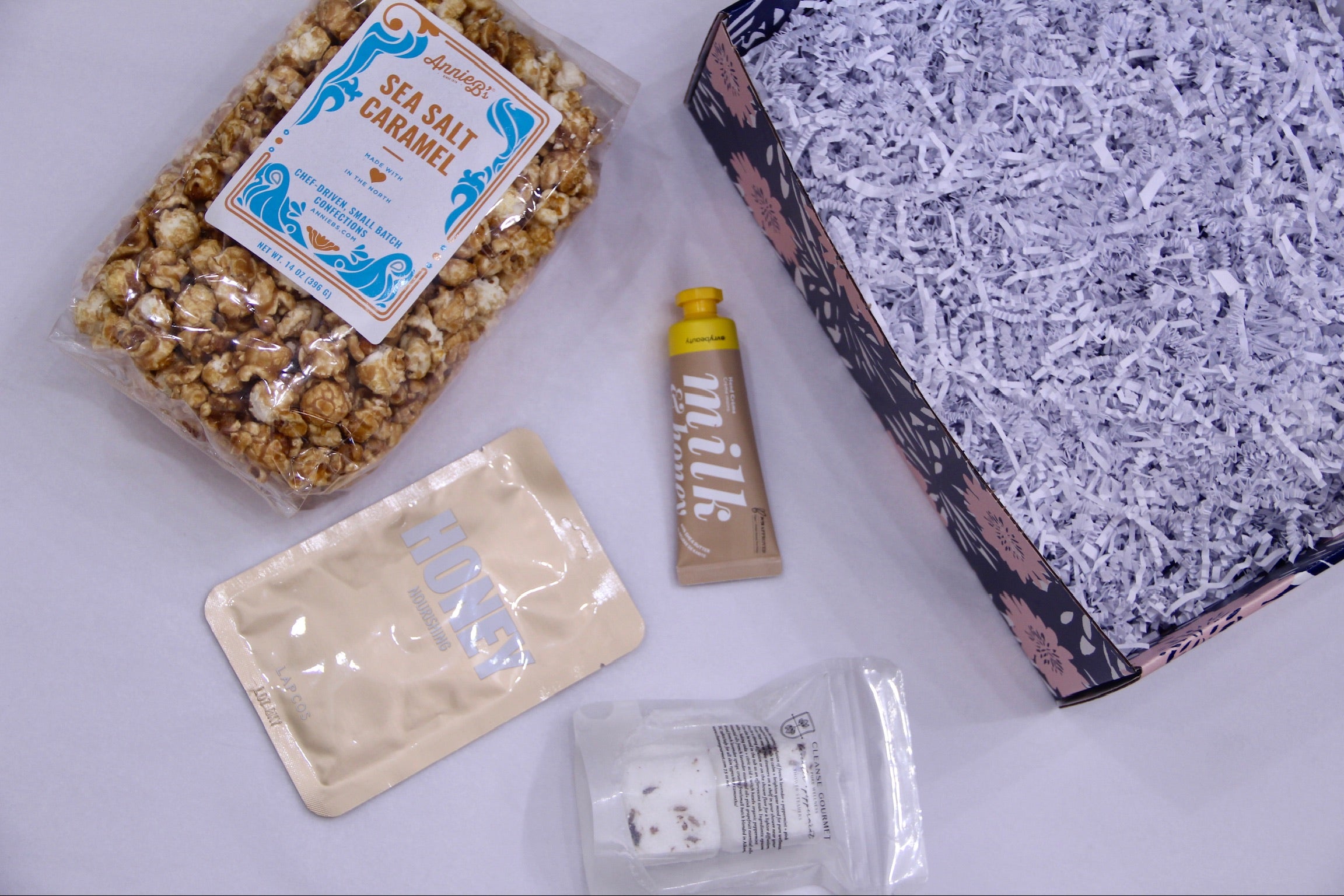 Sea salt caramel popcorn bag, honey facesheet mask, shower steammer, milk & honey hand cream, boxfilled with crinckled paper