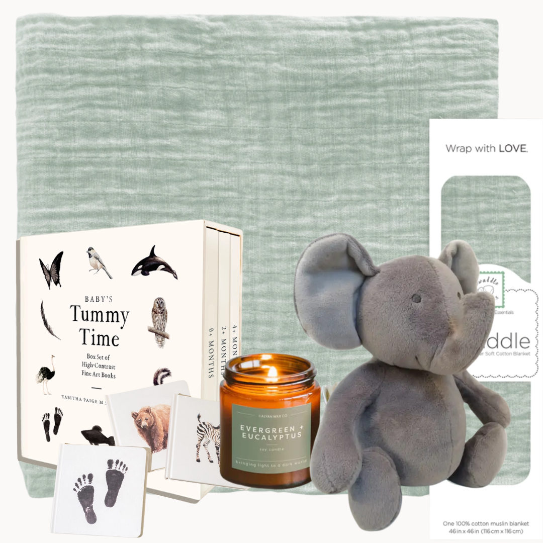 Baby gift set with book, candle, and plush toy on a textured surface
