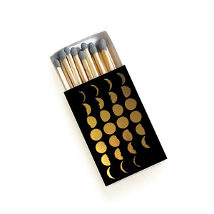 Matches with decorative black box featuring gold moon phases on a white background