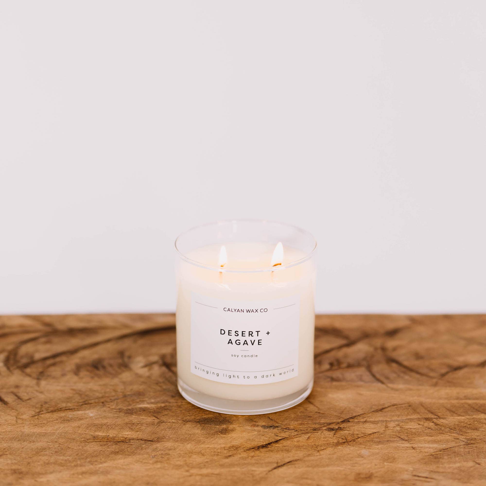 Candle labeled 'Desert Agave' from Calvin Wax Co on a wooden surface with a white background
