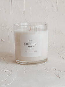 A single-wick soy candle with a clear glass jar, labeled 'Coconut Milk' with a white and green label design, on a white background.