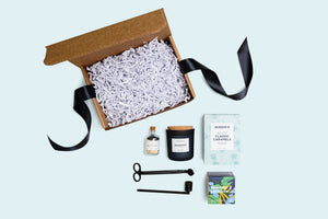 black candle trimmer and snuffer, black headed matches jar, candle, salty classic caramels, lavender  planting kit. open box filled with crinkled paper